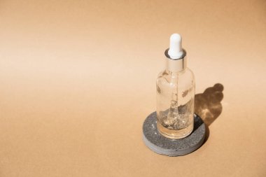Dropper glass Bottle Mock-Up on beige cosmetic podium. Body treatment and spa. Natural beauty products. Eco cream, serum, skin care blank bottle. Anti-cellulite massage oil. Oily cosmetic pipette.