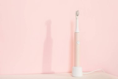 Yeni modern ultrasonik diş fırçası. Çene modeli ve pembe pastel arka planda diş bakımı malzemeleri. Ağız temizliği, diş ve diş sağlığı, sağlıklı dişler. Diş ürünleri Ultrasonik titreşim diş fırçası