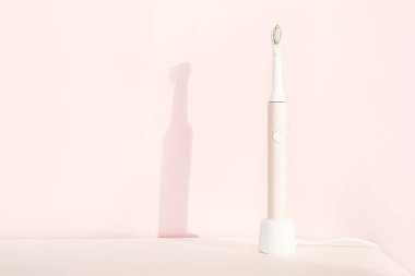 Yeni modern ultrasonik diş fırçası. Çene modeli ve pembe pastel arka planda diş bakımı malzemeleri. Ağız temizliği, diş ve diş sağlığı, sağlıklı dişler. Diş ürünleri Ultrasonik titreşim diş fırçası