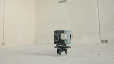 Lazer seviyesi, inşaat, odada bitirme işi. Evin duvarında yeşil kirişler ve çıplak çimento olan lazer bina seviyesi..