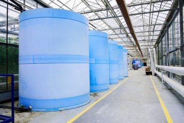 Electric motor water pump at greenhouse. Interior and equipment with pipelines and water tank in modern greenhouse. Modern greenhouse equipment for drip irrigation. Plant growth liquid tanks