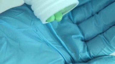 Tabletleri tıbbi eldivendeki bir ele dök. Haplar yakın plan. Sağlık konsepti. Vitaminler ve besin takviyeleri 