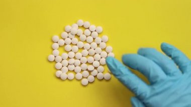 Bir doz hap. Eldivenli bir el hapları serer.