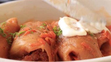 Ekşi kremalı lahana dolması. Lahana rulolarının olduğu bir kaseyi kapat. Lokantada yemek, kes ve bir parça al. Lezzetli.