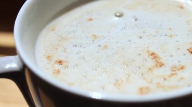 Sabah kahvesi. Beyaz bardakta Latte, yakınlaştırma videosu. Köpüklü canlandırıcı bir içecek.