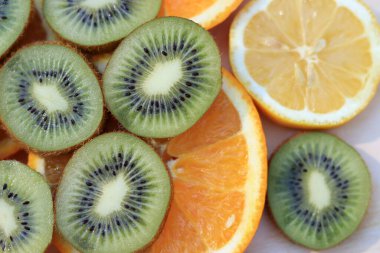 Dilimlenmiş kivi, portakal ve limon dilimlerinin üzerine serilmişti. Olgun meyveler üst üste dizilmiş. Meyve salatası ve taze meyve suyu için malzemeler