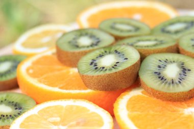 Dilimlenmiş kivi, portakal ve limon. Olgun meyveler yan yana dizilmiş. Seçici odak