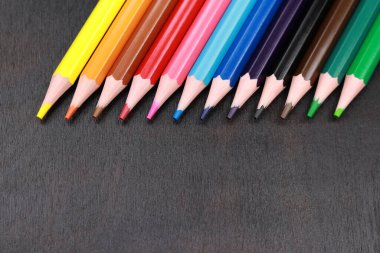 Seçici odaklanma. Siyah ahşap arka planda renkli kalemler. Keskinleştirilmiş parlak kalemler. Çizim ve öğrenme. Okula geri dön.