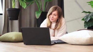Kız evde rahat bir atmosferde dizüstü bilgisayarda çalışıyor. Evden uzak çalışma, blog yazma, internet üzerinden iletişim. Bir dizüstü bilgisayarda metin yazdır
