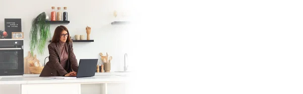 Horizontal banner with a girl in a business suit near a laptop in the kitchen. White space on the banner for your text. Business and finance combined with household chores. Work from home