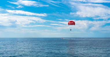 Parasailing denizde yaygın bir açık hava aktivitesidir. Denizdeki bir teknenin arkasında paraşütle uçmak. Güzel deniz manzarası. Deniz kenarında yaz tatili. Seçici odak.