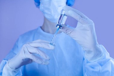 Kadın doktor ya da hemşire ellerinde şırınga ve iğne tutuyor. Grip ve koronavirüs aşısı. Neon renkli fotoğrafçılık. Yakın plan..