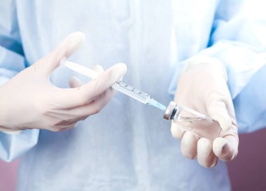 Coronavirus ve grip aşısı. Doktor ya da hemşire şırınga ve şırıngayı ellerinde tutuyor. Yakın plan..