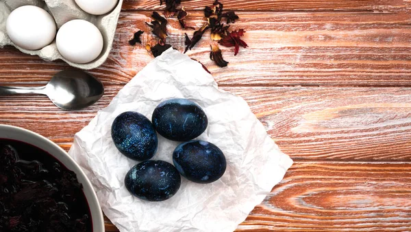 Easter eggs painted with natural dye in blue on the table. The process of dyeing eggs with natural food coloring at home. Close-up. Top view. Copy space.