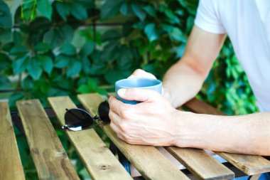 Genç adam kafede bir fincan kahveyle masada oturuyor. Yakın plan..