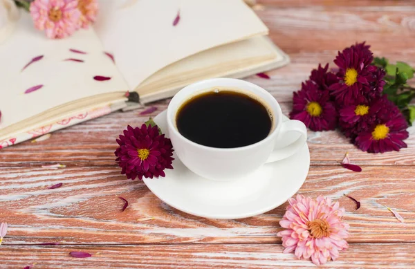 Tahta bir masada beyaz bir fincan kahve ve kasımpatı. Bahar sabahı kahvesi. Hayat konsepti. Yakın plan..