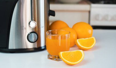 Mutfaktaki masada taze sıkılmış bir bardak portakal suyu ve olgun portakallar. Evde lezzetli ve sağlıklı meyve suları var. Seçici odaklanma. Yakın plan..