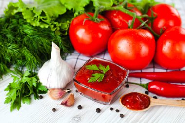 Cam kasede kırmızı sos ya da ketçap ve ahşap bir arka planda yemek, domates, sarımsak, fesleğen, maydanoz, kırmızı acı biber ve baharatlar için malzemeler. Yakın plan..