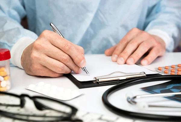 Male doctor gives consultation to patient and fills medical documentation in a hospital. The concept of healthcare and medicine. Close-up. Selective focus.