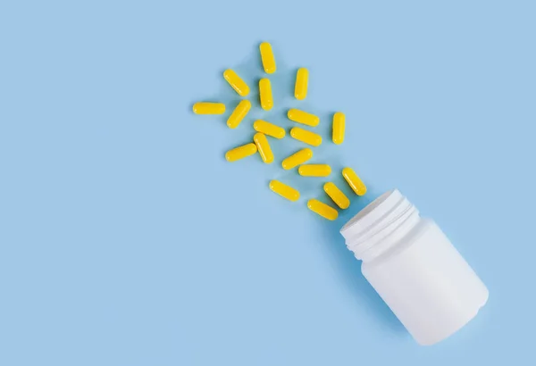 Összetétel Szétszórt Sárga Tabletták Fehér Palack Kék Alapon Orvosi Fogalom — Stock Fotó