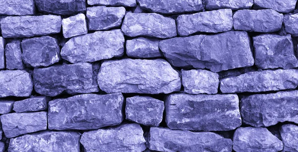 2022 Çok Peri renginde boyanmış taş bir duvarın dokusu. Doğal ve soyut duvar kağıdı. Boşluğu kopyala.