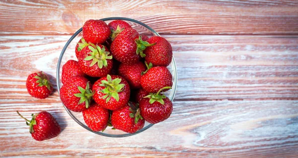 Tahta bir arka planda taze toplanmış çilek kasesi. Uzayı kopyala Yakın plan. Üst görünüm.