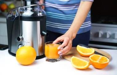 Kadın eli bardağı taze sıkılmış portakal suyuyla tutuyor. Evde doğal ve sağlıklı meyve suları. Yakın plan..