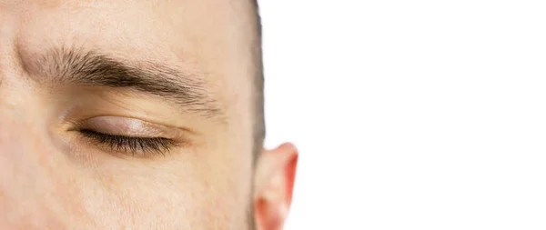 Beyaz bir arka planda genç bir adamın gözleri kapalı. Meditasyon, rahatlama ve dinlenme. Pankart. Yakın plan. Uzayı kopyala Seçici odak.