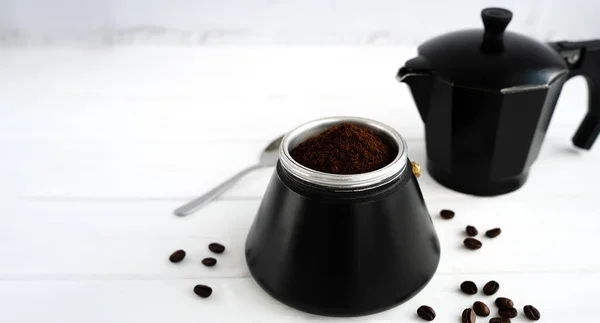 Aromatic freshly ground coffee in a black geyser coffee maker on a white wooden table. Natural coffee. Coffee day. Selective focus.