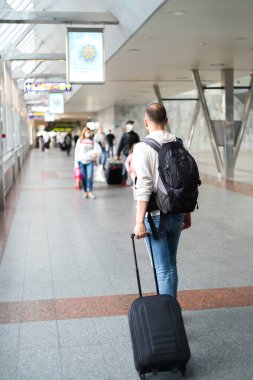 Sırt çantalı ve bavullu genç bir turist havaalanında ya da tren istasyonunda. Uzayı kopyala Seçici odak.