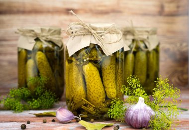 Homemade preserved cucumbers in jars on a wooden background. Rustic style. Delicious homemade pickled. Close-up.