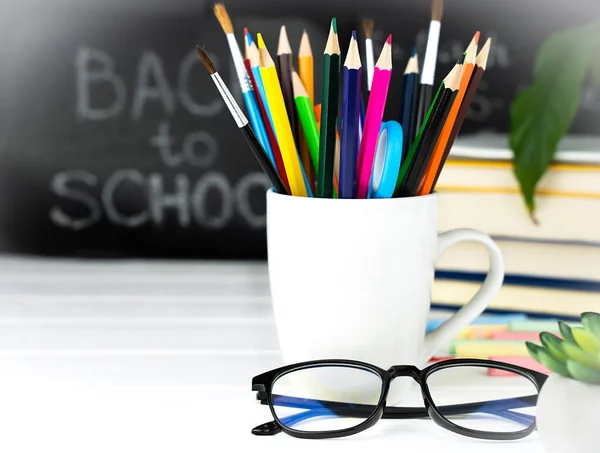 Teacher\'s Day holiday concept. School stationery, glasses and a chalkboard in the background. Back to school. Close-up. Copy space. Selective focus.