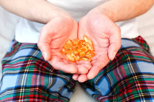 Young man holds a handful capsules of Omega-3 fatty acid in his hands. Taking vitamins, supplements. Healthy lifestyle. Healthy eating. Close-up.