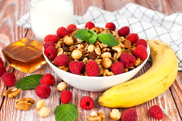 Granola, fresh raspberries and banana for breakfast on the table. Healthy breakfast in the morning. Close-up.