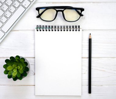 Workplace with blank notepad, glasses, pencil and keyboard. Mockup. Flatlay. Top view. Place for text.