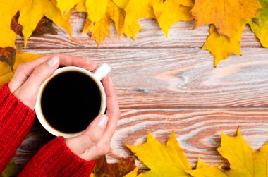 Woman's hands hold a cup of hot aromatic coffee. Autumn background. Flatlay composition. Hello fall. Selective focus.