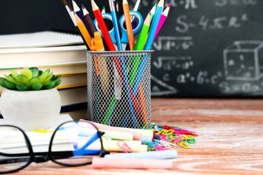 School supplies, books, glasses and a blackboard in the background with mathematical formulas. Back to school. Close-up. Selective focus.