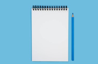 Blue pencil and blank notebook on a blue background. Mockup. Flatlay. Top view. Copy space.