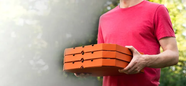 Delivery service. A pizza delivery man holds pizza boxes. Banner. Mockup. Copy space. Selective focus.