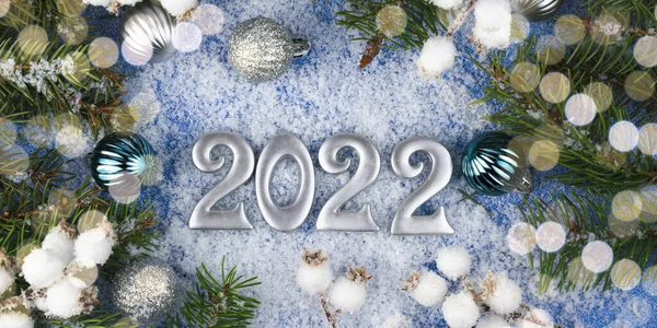 Happy New Years 2022. Winter New Years composition with number 2022 and a Christmas decor on snowy background. Flatlay. Close-up.