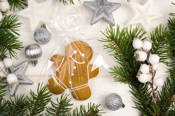 Festive composition with packed gingerbread men and Christmas tree on a white wooden background. Place for text. Top view.