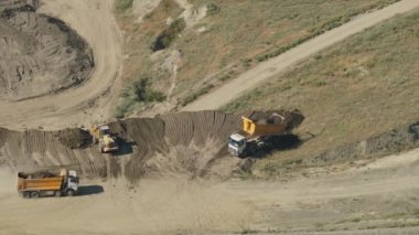 8K 7680X4320 4320p.Çöp kamyonları toprağı vadiye boşaltır. Sarı kamyon boşalır. Kum, çakıl ya da inşaat için toprak gibi gevşek maddelerin taşınması için kullanılan çöp kutusu. Çöp kazma kazıları.