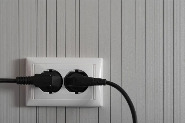 導電性ワイヤとプラグを備えた灰色の壁の白い電気コンセント — ストック写真