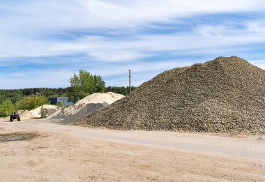 Yeni bir otoyol inşaatı için kum, taş ve çakıl yığınları. Yol boyunca bir traktör sürüyor..