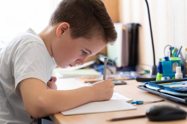 Çocuk evde uzaktan bilgisayar ve internet kullanarak ders veriyor..