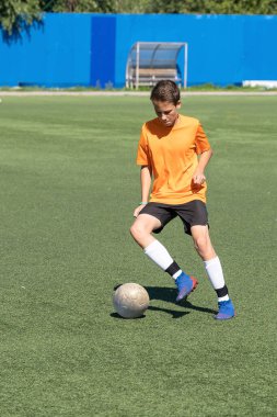 Çocuk futbol oynamayı, yapay sahada topla antrenman yapmayı ve gol atmayı seviyor, çocuk futbol oynuyor..