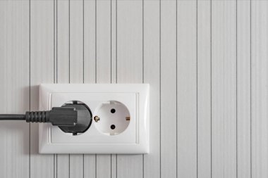 Gri bir duvarda iletken kablolar ve prizlerle beyaz elektrik prizi..