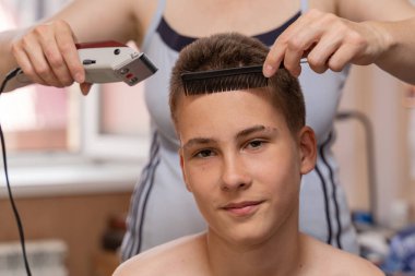 Kilitlenme ve koronavirüs salgını yüzünden genç bir adamın saçını kesmek. Ebeveynler ve akrabalar kuaföre gitmeden birbirlerine saçlarını yaptırmaya yardım ederler..