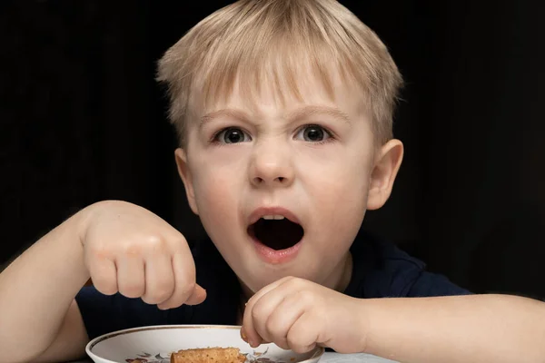 Küçük çocuk. 3 yaşında sarışın beyaz, siyah arka planda waffle tüpü yiyor. Küfür ediyor, bağırıyor, rahatsız oluyor..