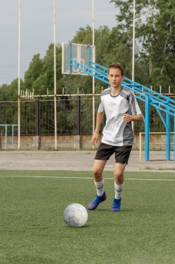 Çocuk futbol oynamayı, yapay sahada topla antrenman yapmayı ve gol atmayı seviyor. Çocuk futbol oynuyor..